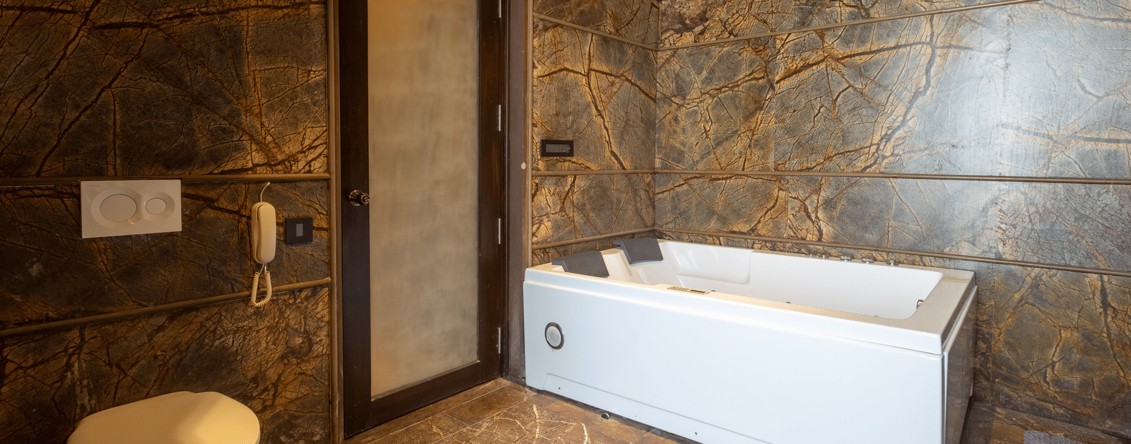 A luxurious bathroom at Aamaghati Wildlife Resort featuring an elegant bathtub, modern fittings, and a natural stone finish for a relaxing stay.