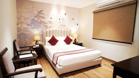 Guest room with bed, wall artwork, chairs, and window blinds at Nirvana Gateway.