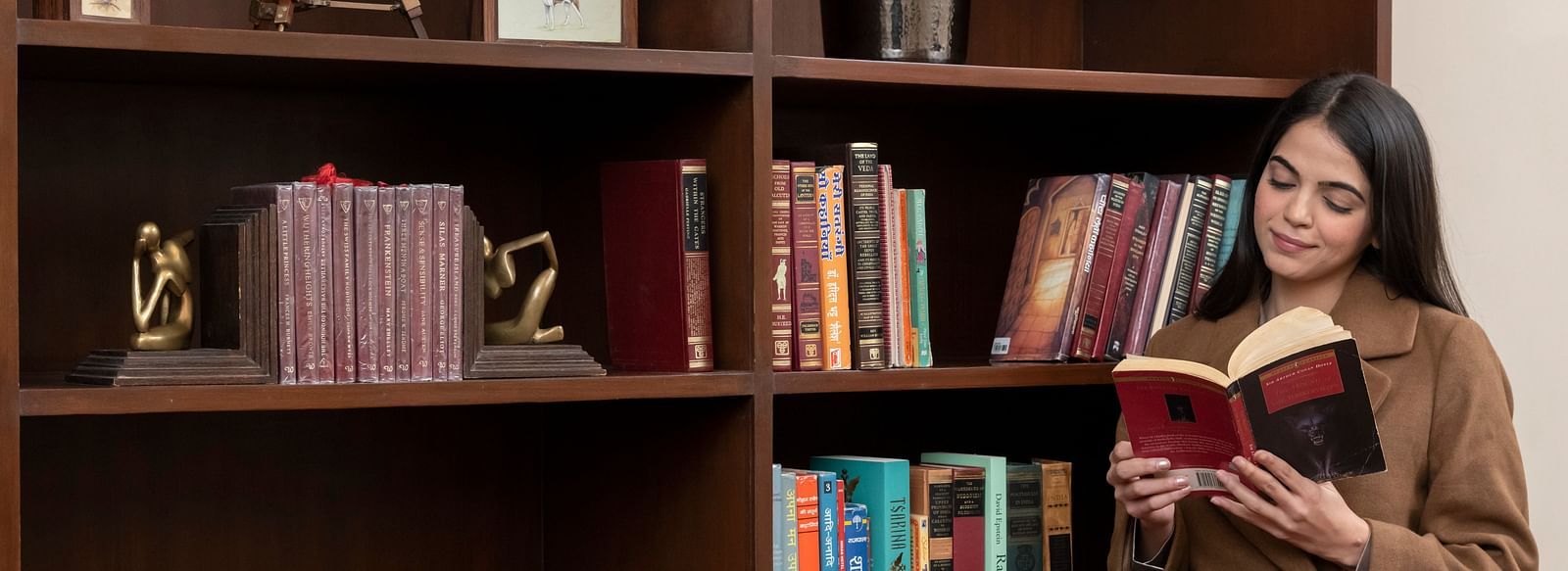 a woman going through a book at the library at The Claridges Nabha Residence