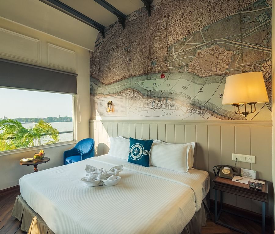 a well made bed with blue pillows with a lamp hung above it - polo floatel kolkata