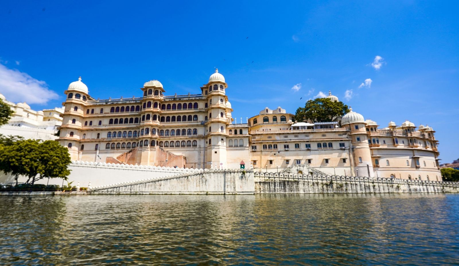 An overview of City Palace as seen from Lake Pichola with blue sky in the background
