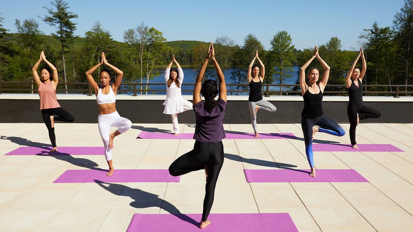 7 women performing yoga on the rooftop