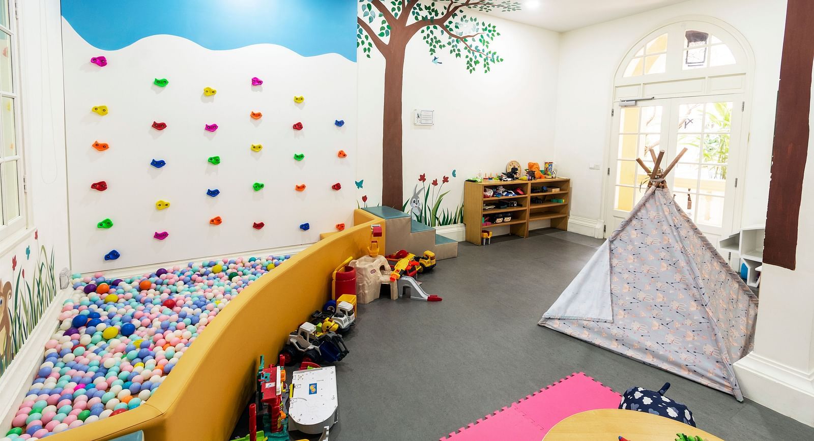 A colourful and playful children's playroom with a tree mural and various toys | Central Mansions, Phnom Penh