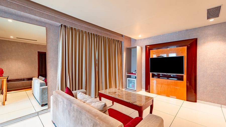 Executive Suite features a large sofa with a table in front and a wall-mounted television opposite it at Crescent Spa & Resort, Indore