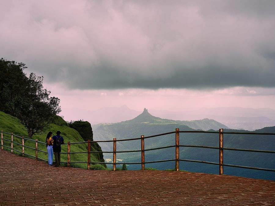 Image featuring two people at a view point, mountains in the background at day time