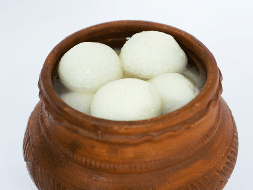 A close up view of a matka (clay pot) filled to the brim with Rosgolla