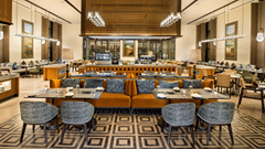 View of CHITHIRAI restaurant at The Residency Signature Madurai with dining tables, blue chairs, patterned flooring, and warm ambient lighting.