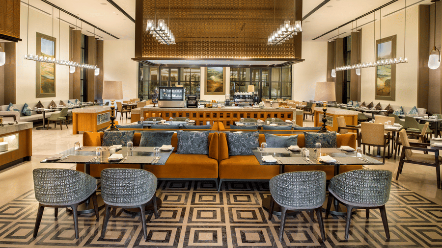 View of CHITHIRAI restaurant at The Residency Signature Madurai with dining tables, blue chairs, patterned flooring, and warm ambient lighting.