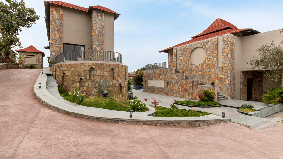 Beautiful stone resort villas with red tiled roofs sit along a paved pathway under a clear, bright blue sky - Sajjan Bagh Resort and Spa, Kumbhalgarh