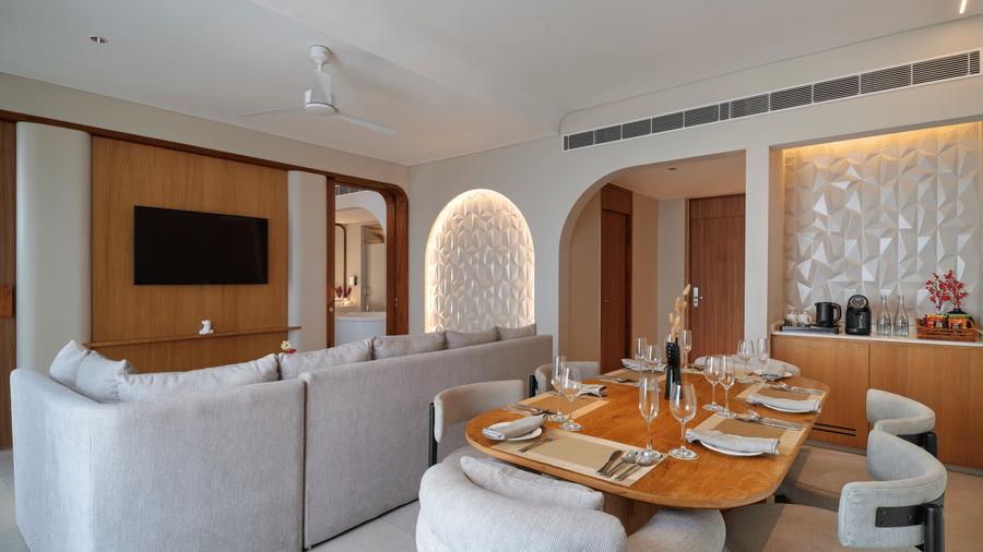 The Intimate Escape Suite living room at Swosti Premium Beach Resorts, Puri, with sofas, a television, chairs, and tables.