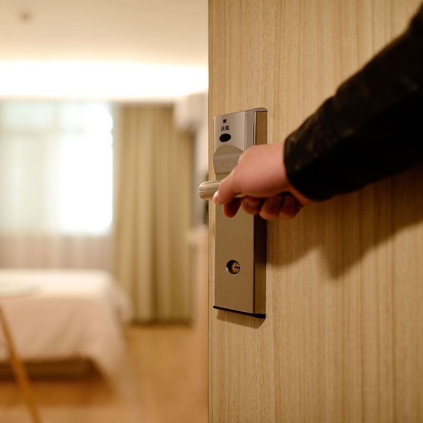 A person opening a door of a hotel room