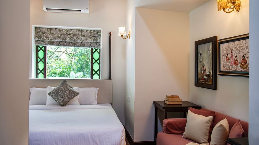 An image of a bedroom featuring a bed, window above the bed, and sofa on the right at Lamrin Ucassaim Hotel, Goa