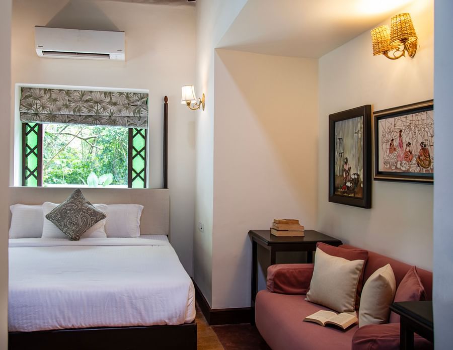 An image of a bedroom featuring a bed, window above the bed, and sofa on the right at Lamrin Ucassaim Hotel, Goa