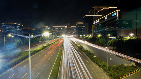 a long exposure picture taken of a road in live mode showing long trails of car lights captured during the night.