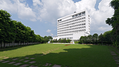 A modern white hotel building standing tall behind a perfectly manicured green lawn with stepping stones leading across it - Clarks Avadh, Lucknow