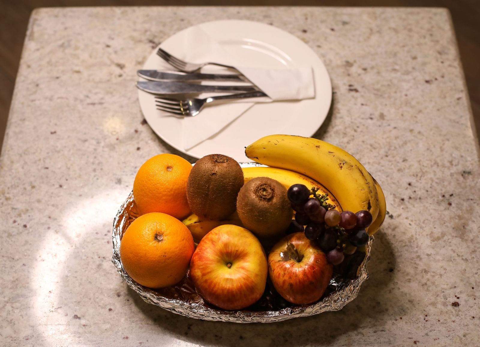 Hotel room amenity with fresh fruit plate including bananas, apples, and a kiwi | Mango Hill Central, Chennai