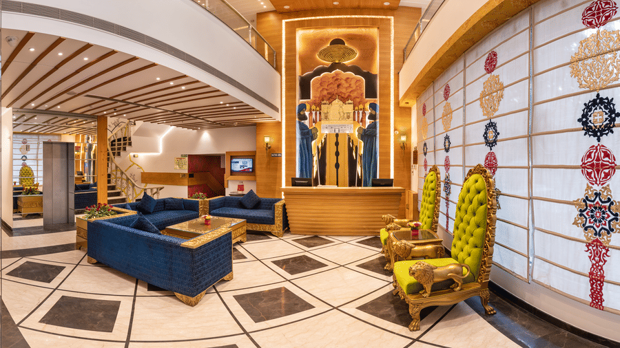 Wide angle view of the lobby at Lords Inn Amritsar with blue sofas, decorative murals, patterned flooring, and warm ambient lighting.