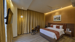 A large bed placed in front of a television in front of a wall-mounted television