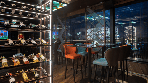 A corner view of dining at Asiatic Rooftop Bar and Restaurant, surrounded by contemporary chairs and illuminated by soft ambient light.