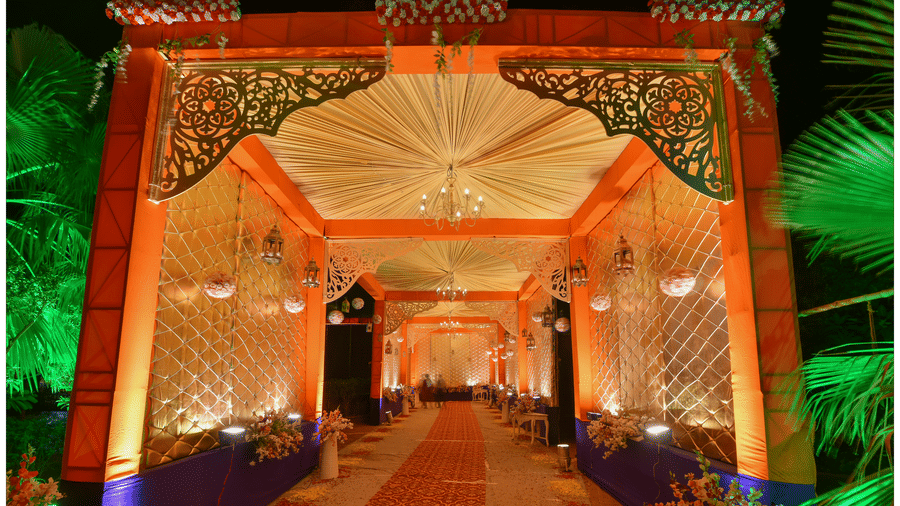A long carpeted walkway passing through a decorative archway lit with lighting at Garh Govind.