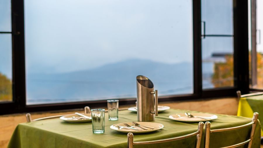A table with neatly places cutlery on it and a glass window overlooking the valleys at Flutter Hotels and Resorts, Lansdowne.