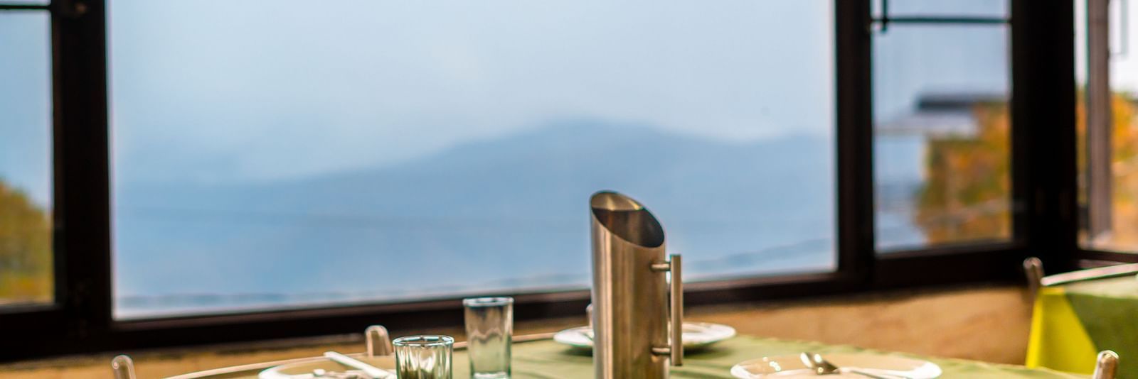 A table with neatly places cutlery on it and a glass window overlooking the valleys at Flutter Hotels and Resorts, Lansdowne.