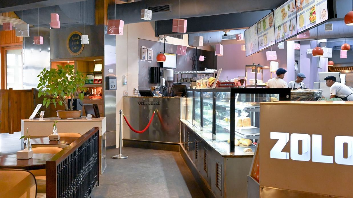 A bakery with a counter full of fresh baked goods, workers behind the counter