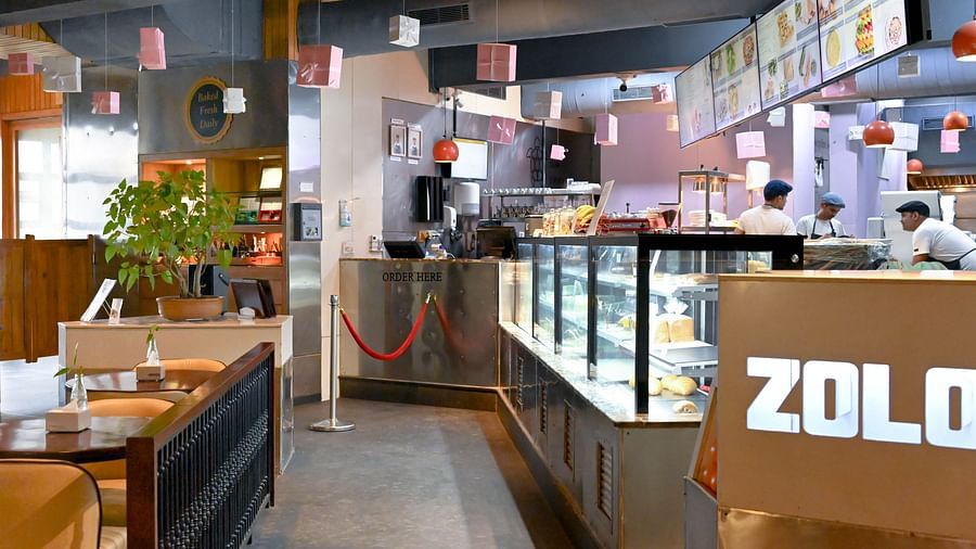 A bakery with a counter full of fresh baked goods, workers behind the counter