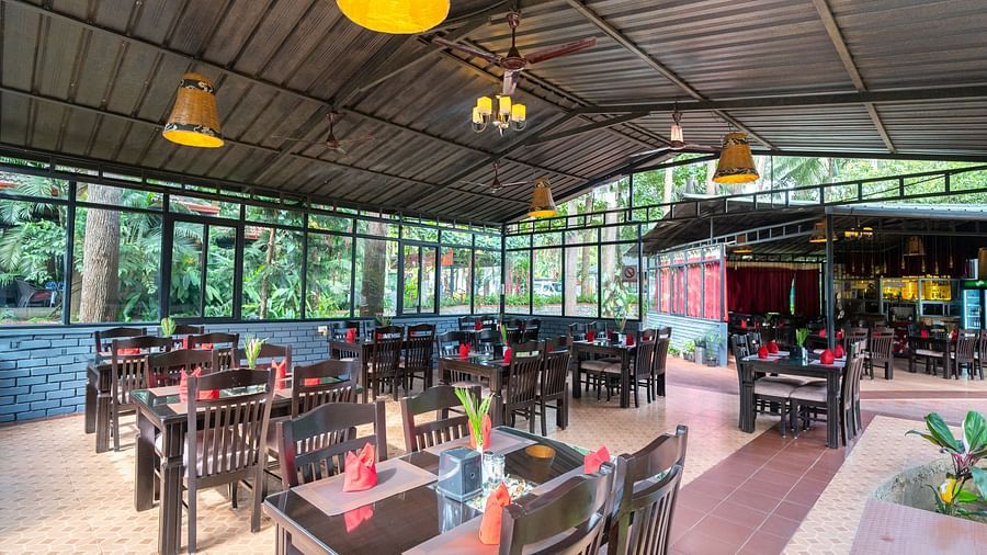 Image of a dining area with wooden tables and chairs at Parampara Resort & Spa, Kushalnagar.