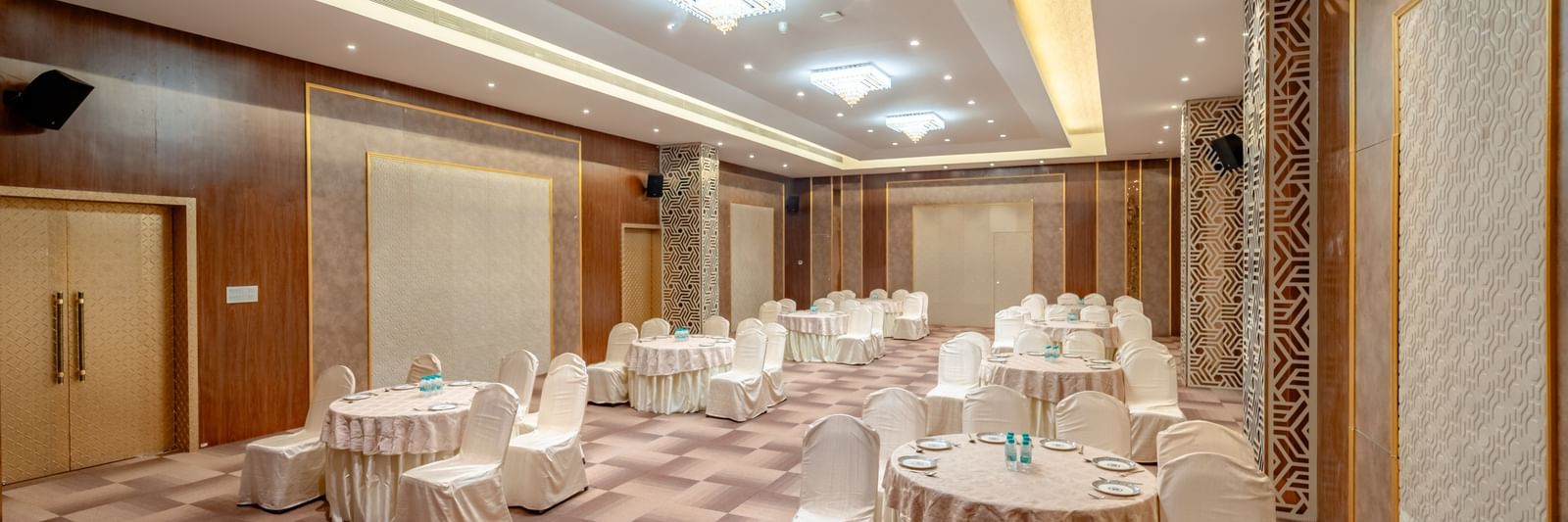 Conference room with round tables and beige chairs, ready for an event | Meetings & Events | Pravasa Hotel, Vijayapura