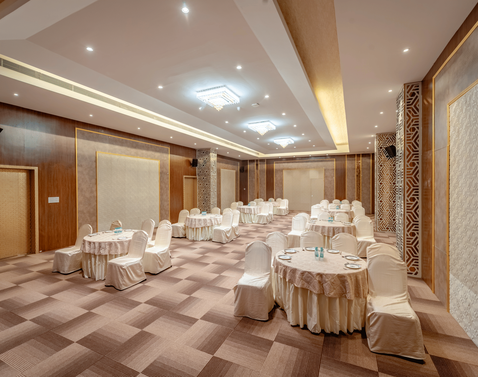 Conference room with round tables and beige chairs, ready for an event | Meetings & Events | Pravasa Hotel, Vijayapura