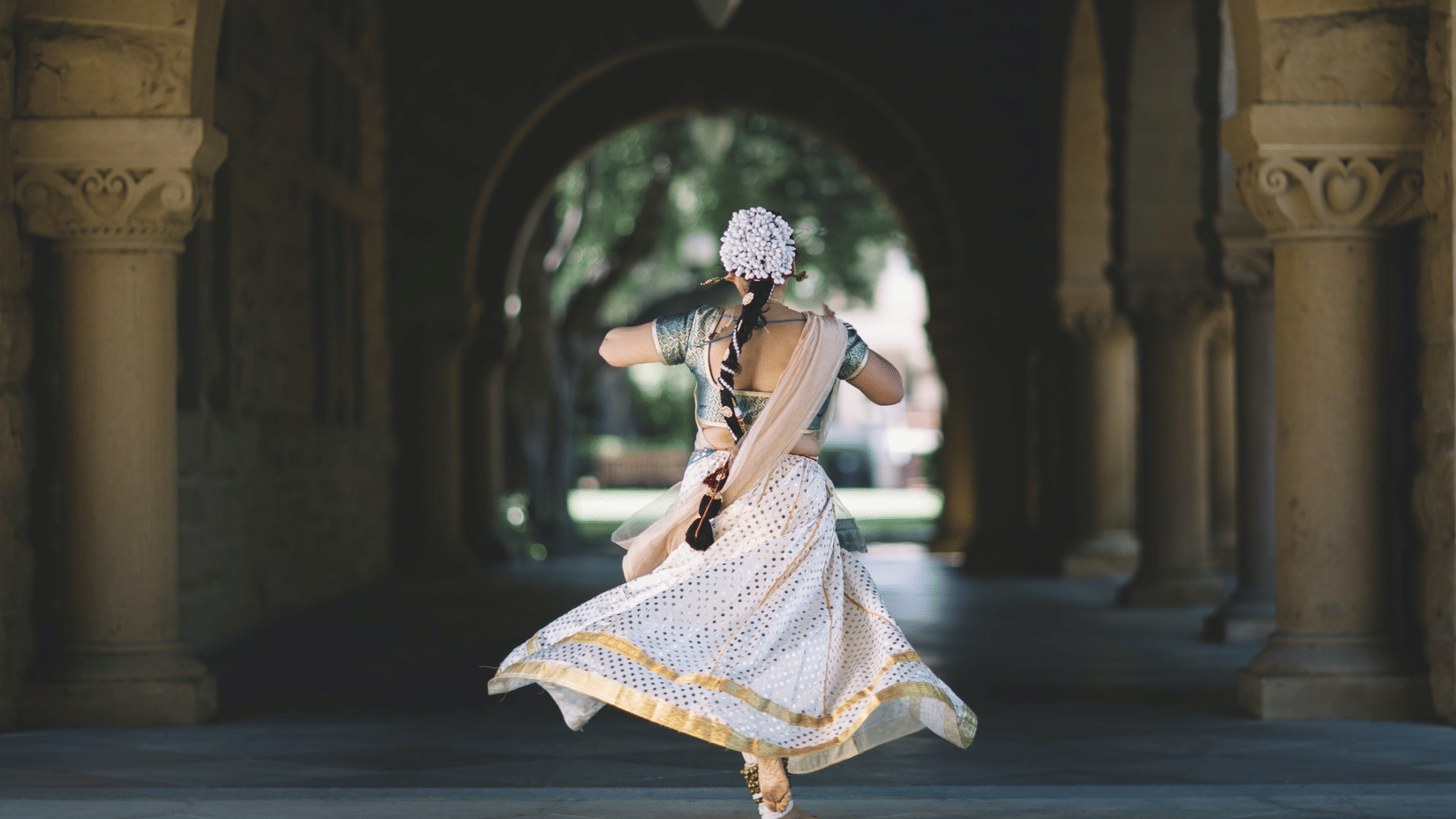 A woman dancing Kathak in front of an archway