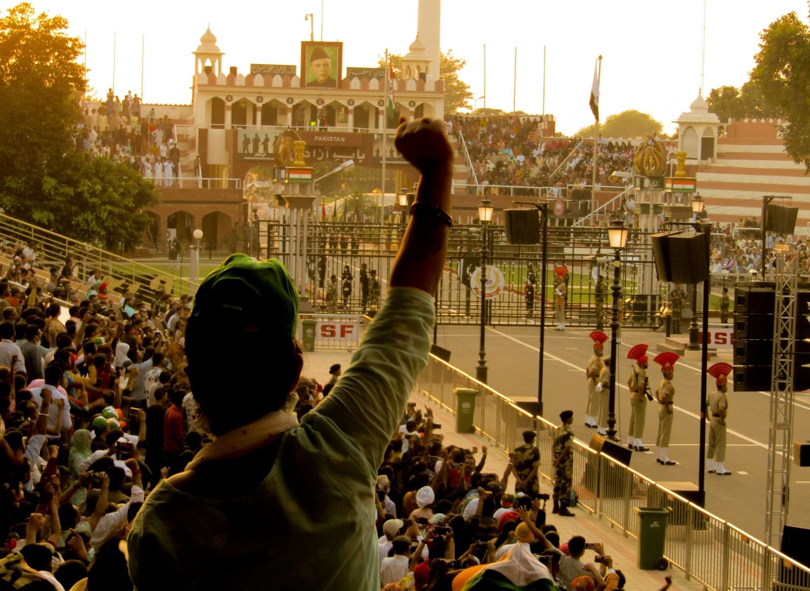 Large crowd gathered at a border crossing ceremony or event, viewed from behind a military guard.