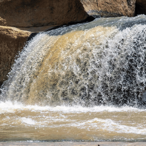 Waterfall cascading over rocky ledges into flowing water