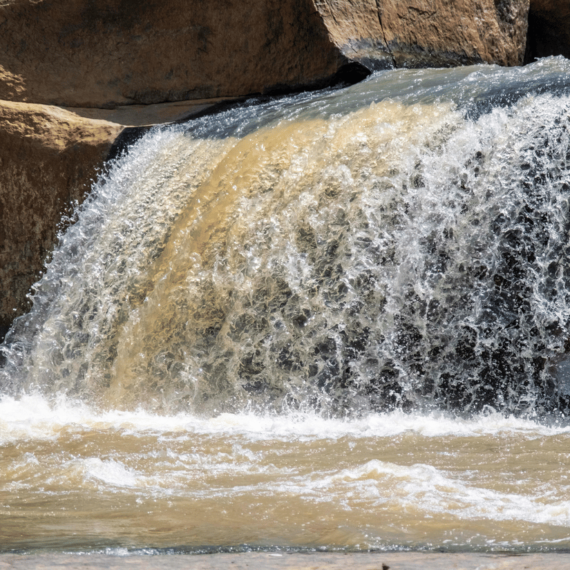 Waterfall cascading over rocky ledges into flowing water