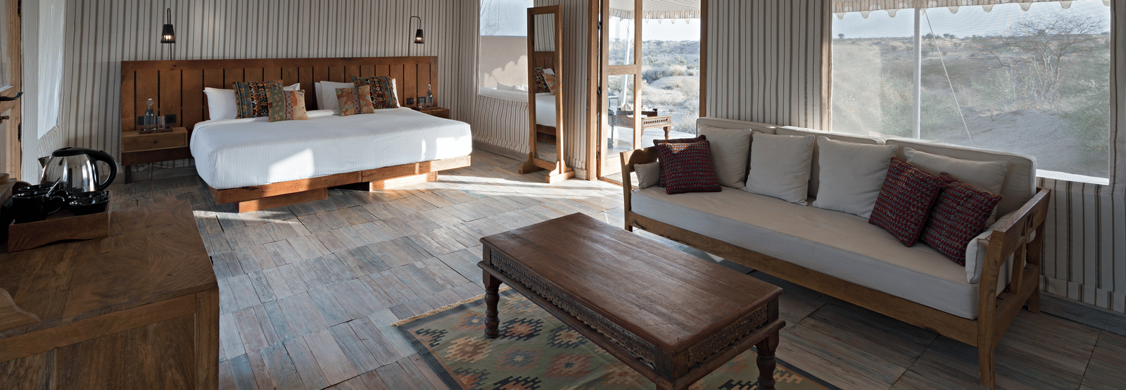 A room with a king bed, a table placed on a carpet and a sofa beside it at MANVAR Kumat Thar Serinity Camp.