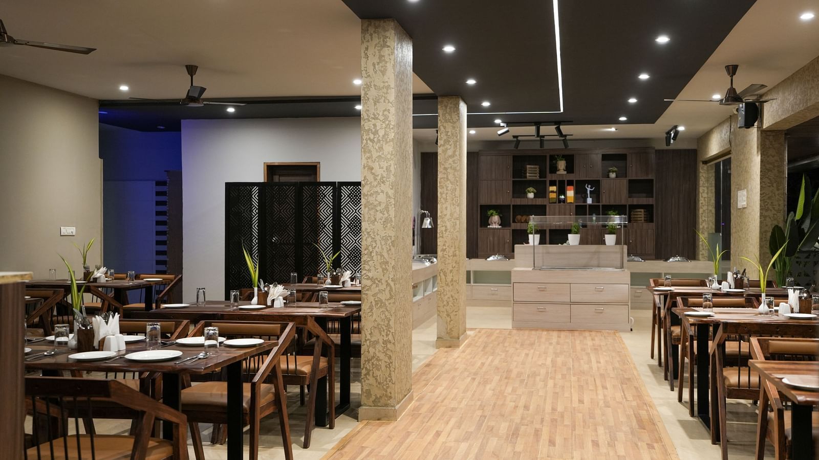 Central walkway between dining tables leading to the buffet counter at the far end at TGI Livancia Hillside, JC Nagar, Mysore