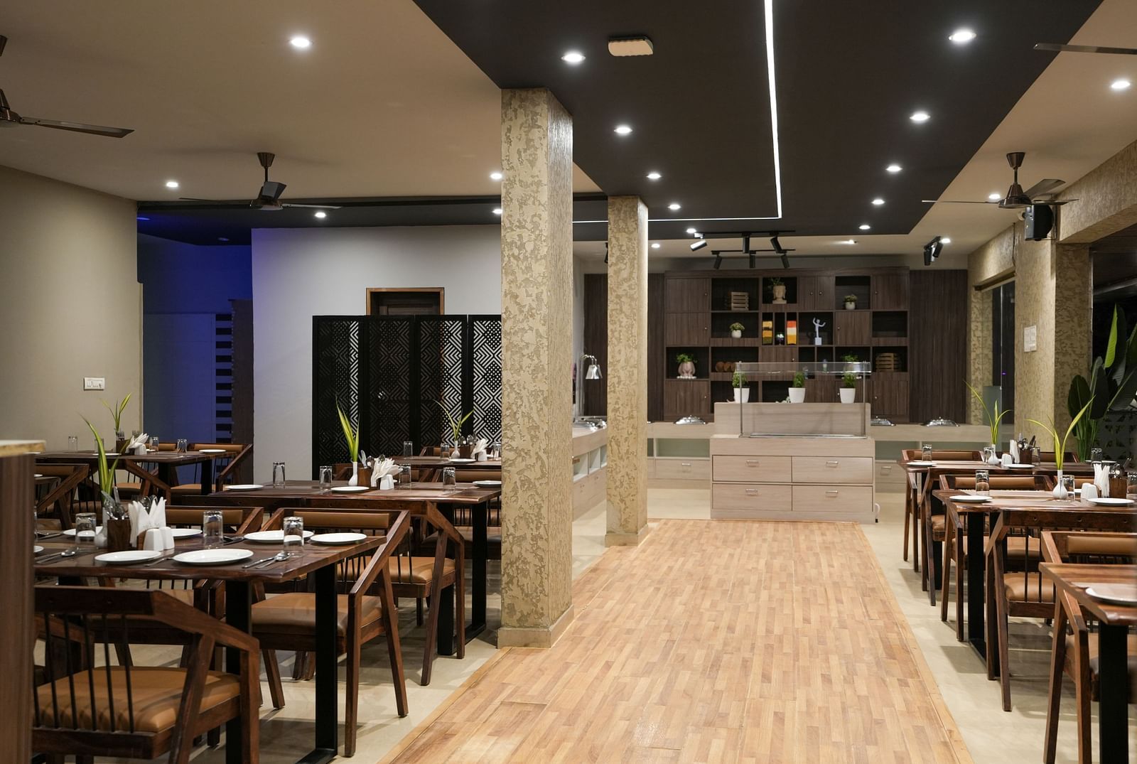 Central walkway between dining tables leading to the buffet counter at the far end at TGI Livancia Hillside, JC Nagar, Mysore