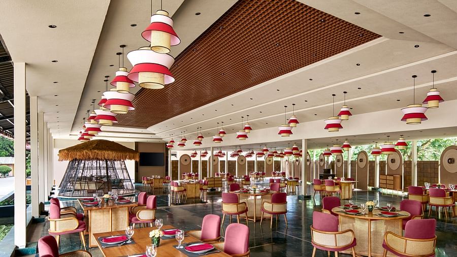A brightly lit interior of Zaika Restaurant with numerous tables and chairs, featuring striking red and white pendant lights at DGV Resort by Treat, Silvassa.