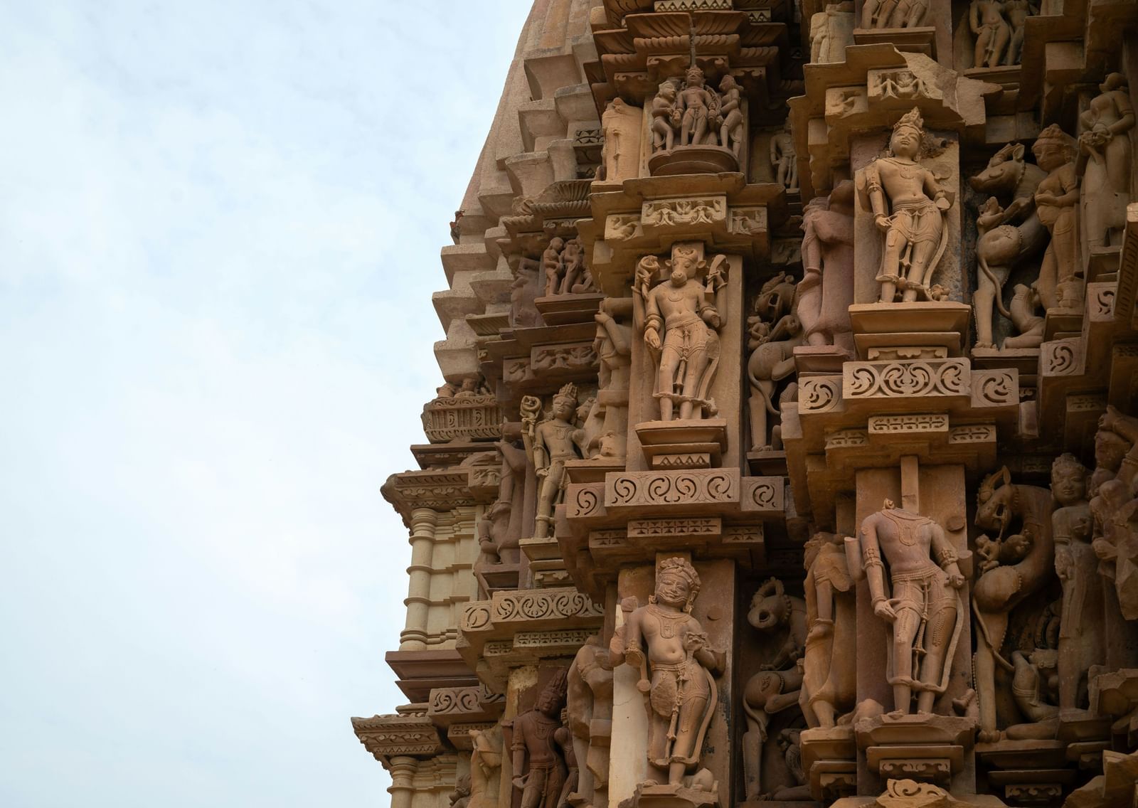 Carvings on a temple seen, with a bright sky in the background.