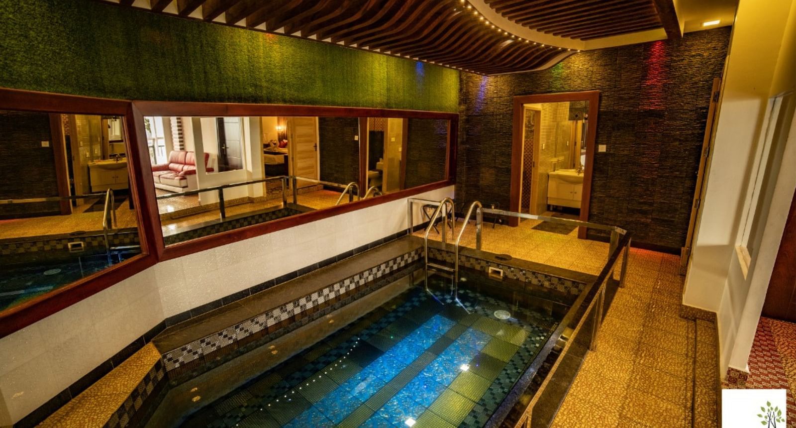 A small swimming pool inside Parakkat Nature Hotels and Resorts surrounded by mirrors on walls and rooms 