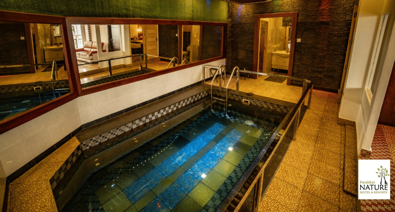 A small swimming pool inside Parakkat Nature Hotels and Resorts surrounded by mirrors on walls and rooms 