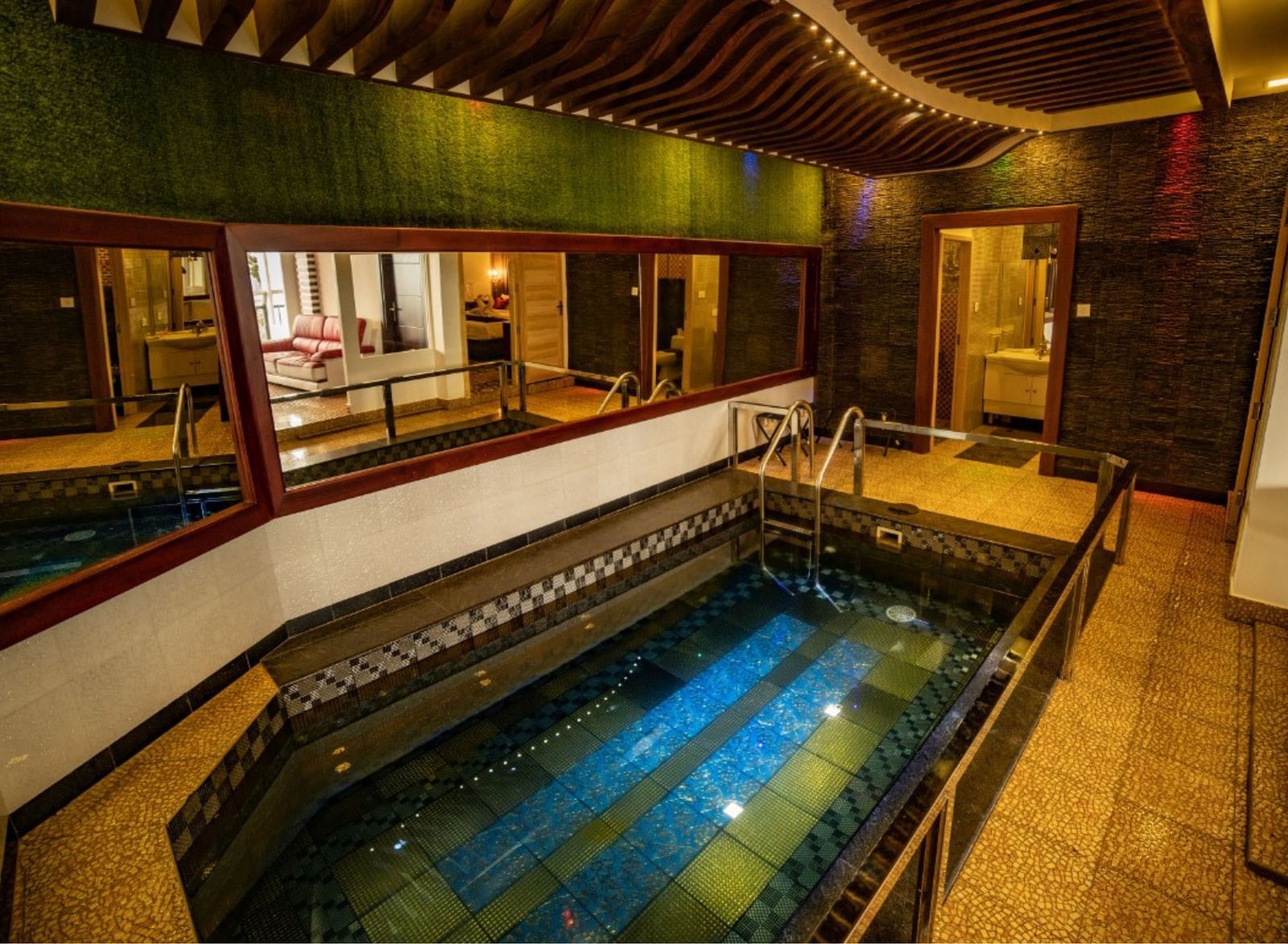 A small swimming pool inside Parakkat Nature Hotels and Resorts surrounded by mirrors on walls and rooms 