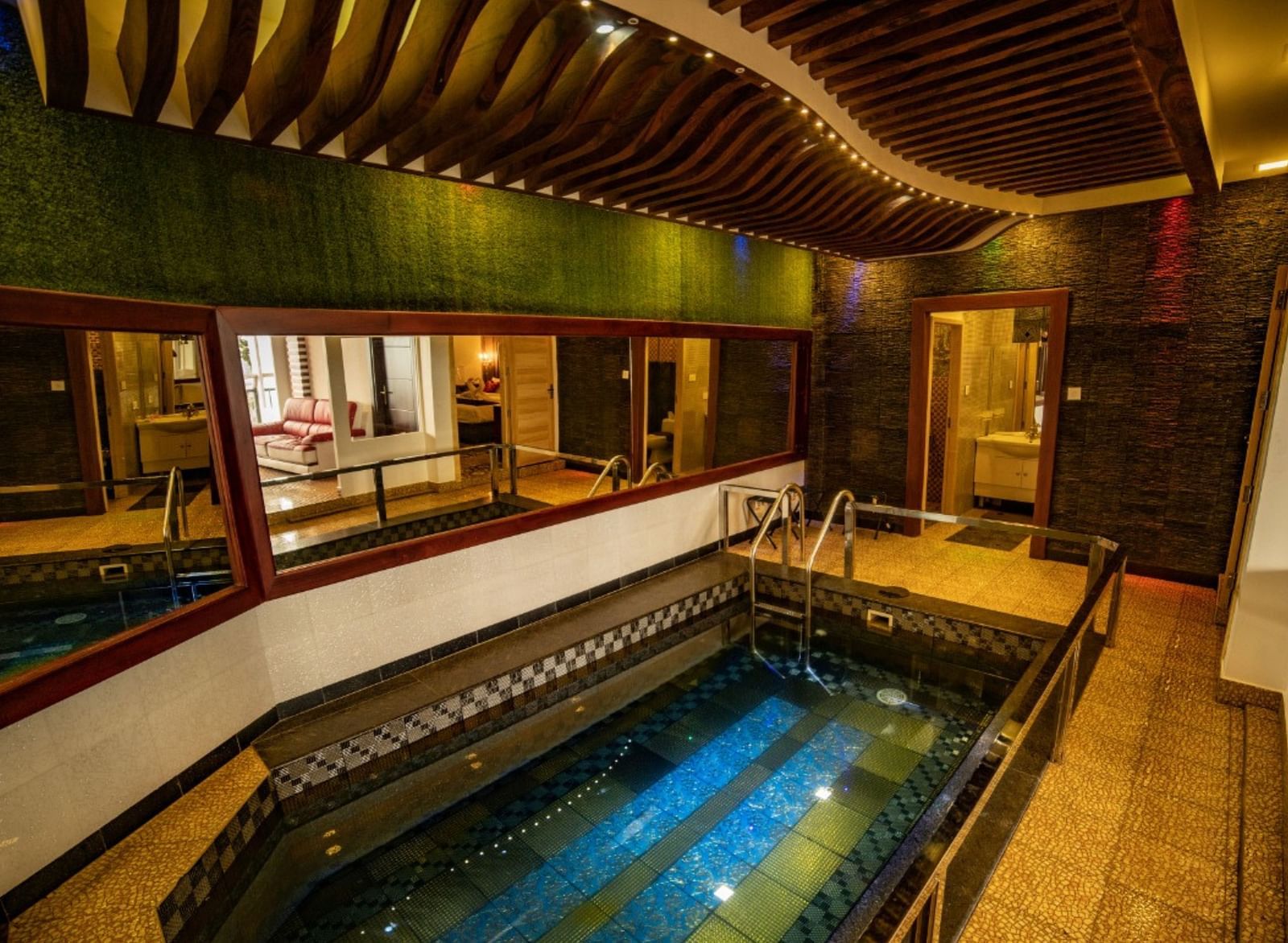 A small swimming pool inside Parakkat Nature Hotels and Resorts surrounded by mirrors on walls and rooms 