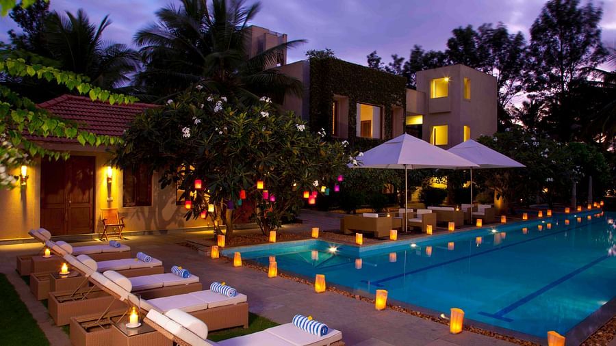 Outdoor evening view of a resort with a pool and lounge chairs, warm lighting - Shreyas Retreat