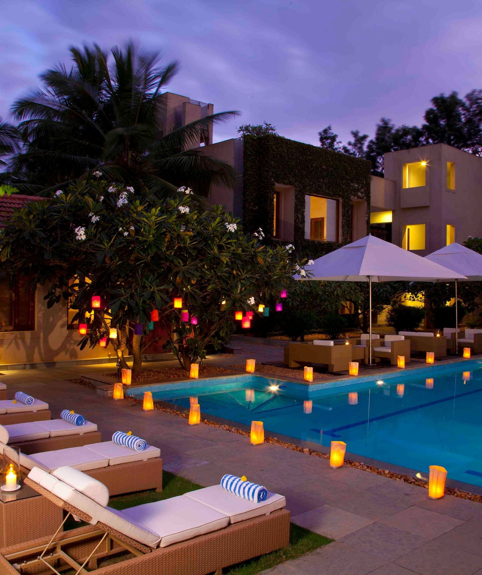 Outdoor evening view of a resort with a pool and lounge chairs, warm lighting - Shreyas Retreat
