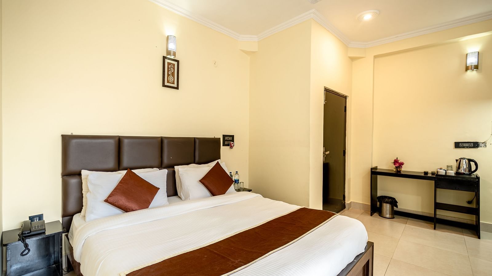 a bedroom at Flutter Hotels & Resorts featuring a bed and desk with kettle