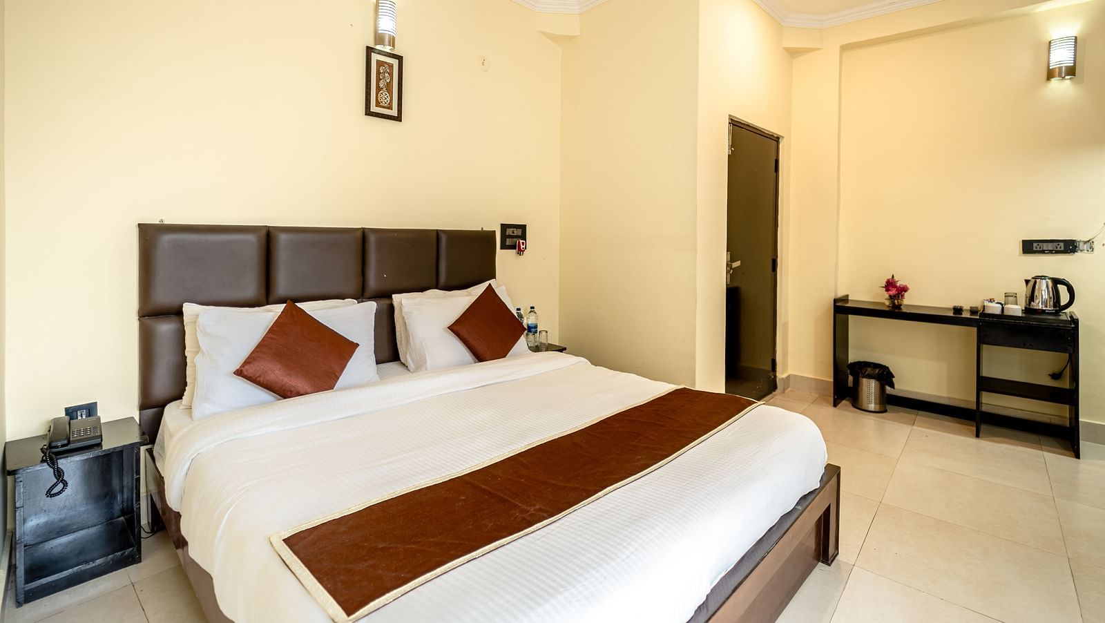 a bedroom at Flutter Hotels & Resorts featuring a bed and desk with kettle