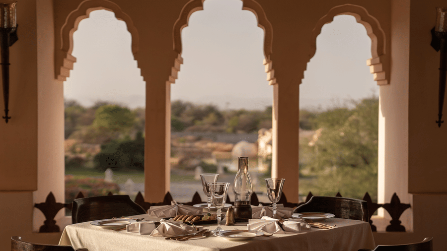 Dining setup with scenic arched window view at Evolve Back Hampi