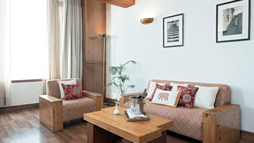 Living room with sofa seating, wooden coffee table, city view window and wooden flooring at Clarks Amer, Jaipur.